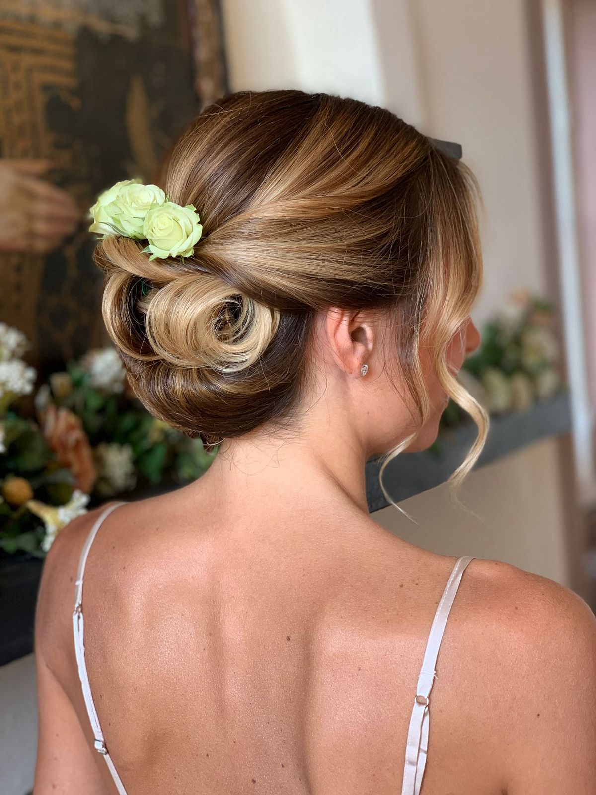 Chignon basso con rose e onde morbide su capelli con riflessi caramello