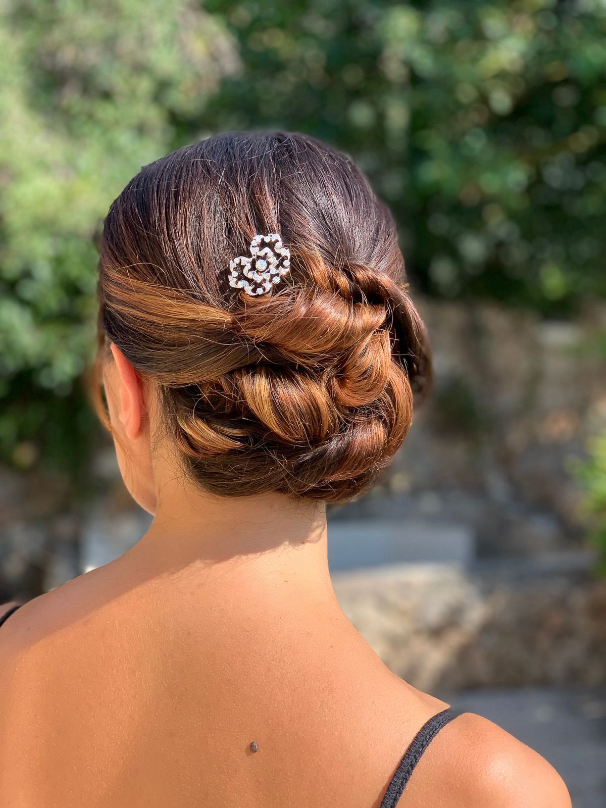 Raccolto basso con intrecci e accessorio in cristallo su capelli castani